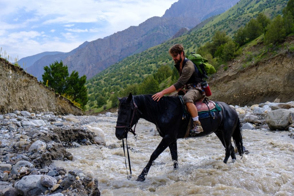 crossing a river by horse in kyrgyzstan